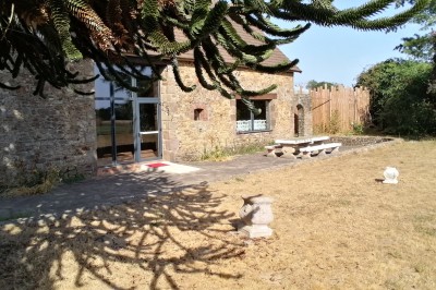 Salle de loisirs avec table de ping-pong, table de jeu blanche, cible de fléchettes et murs en bois et pierre.