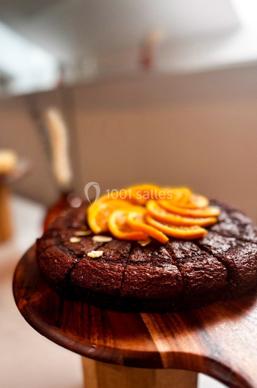 Gâteau au chocolat coupé en parts, garni de tranches d'orange, présenté sur une planche en bois.