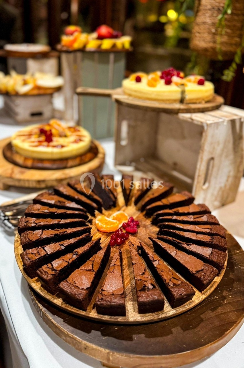 Assortiment de desserts sur une table, avec un gâteau au chocolat tranché au premier plan et des tartes en arrière-plan.