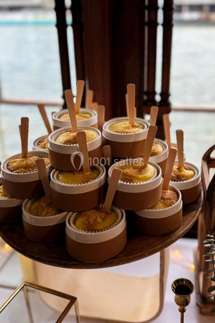 Desserts individuels présentés dans des pots en bois avec des cuillères, disposés sur un plateau près d'une fenêtre.