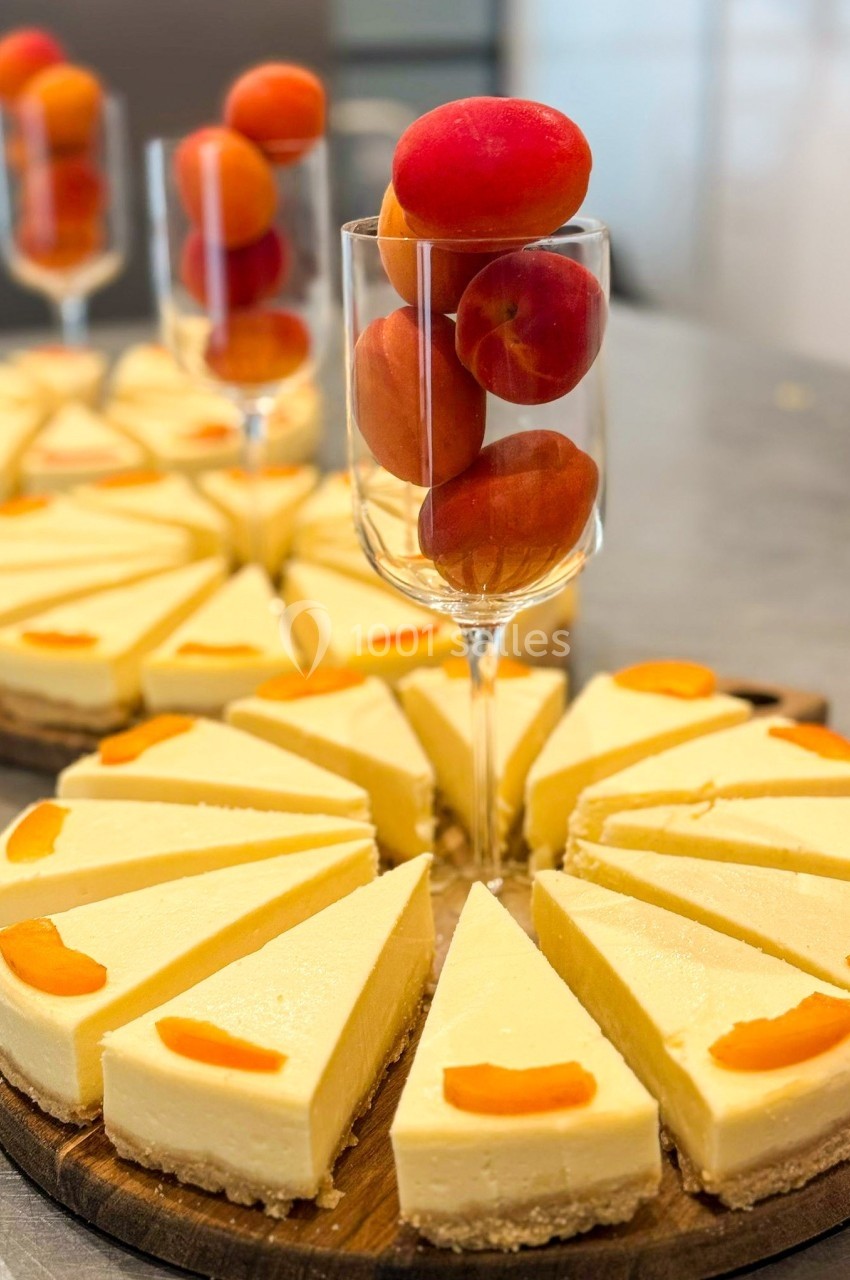 Tranches de cheesecake garnies de morceaux d'abricots, disposées autour d'un verre rempli d'abricots entiers.