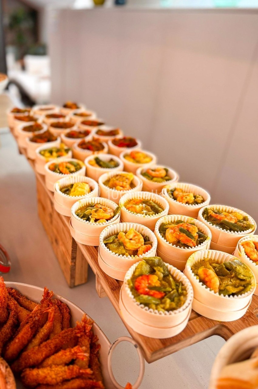 Plateau de bouchées salées variées présentées dans des petits contenants en bois, avec des crevettes en accompagnement.