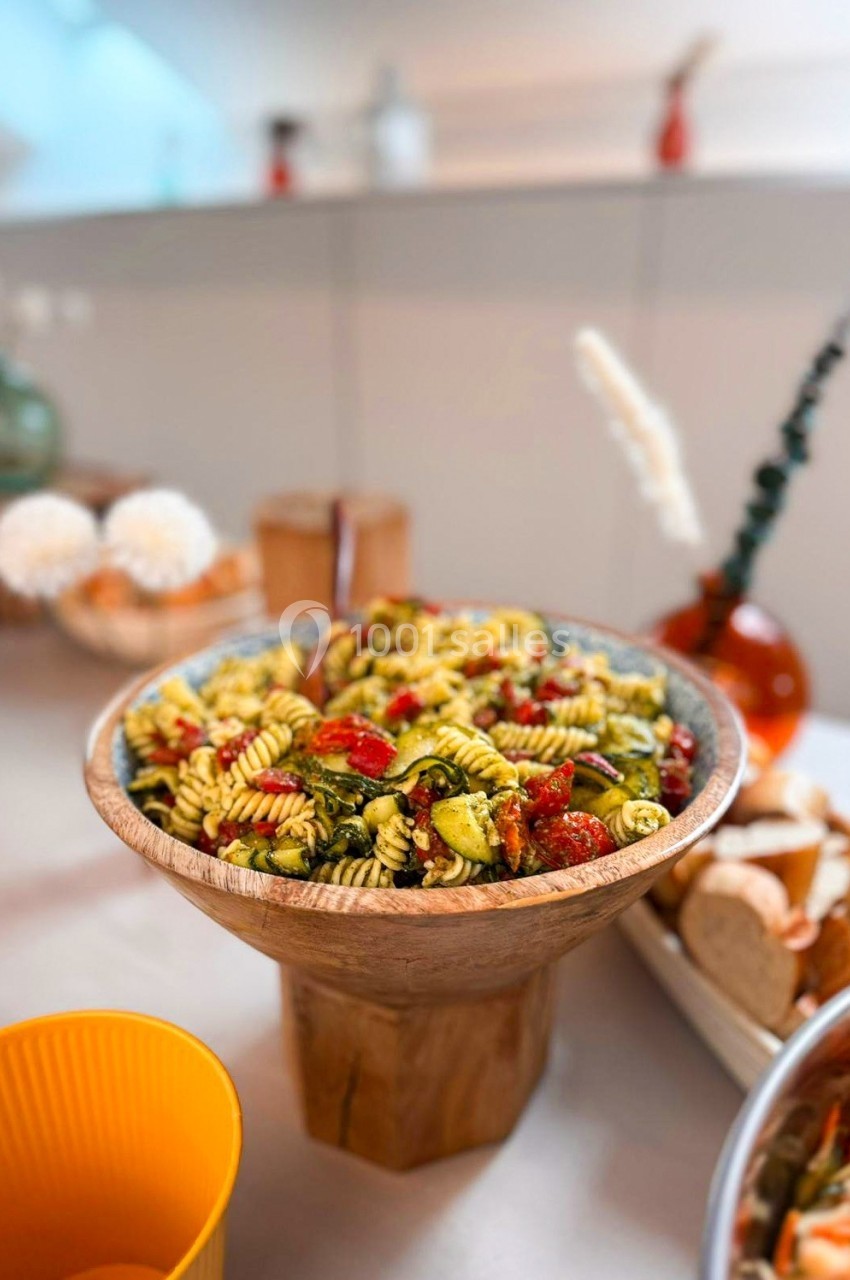 Salade de pâtes colorée avec légumes, servie dans un grand saladier en bois sur une table dressée.