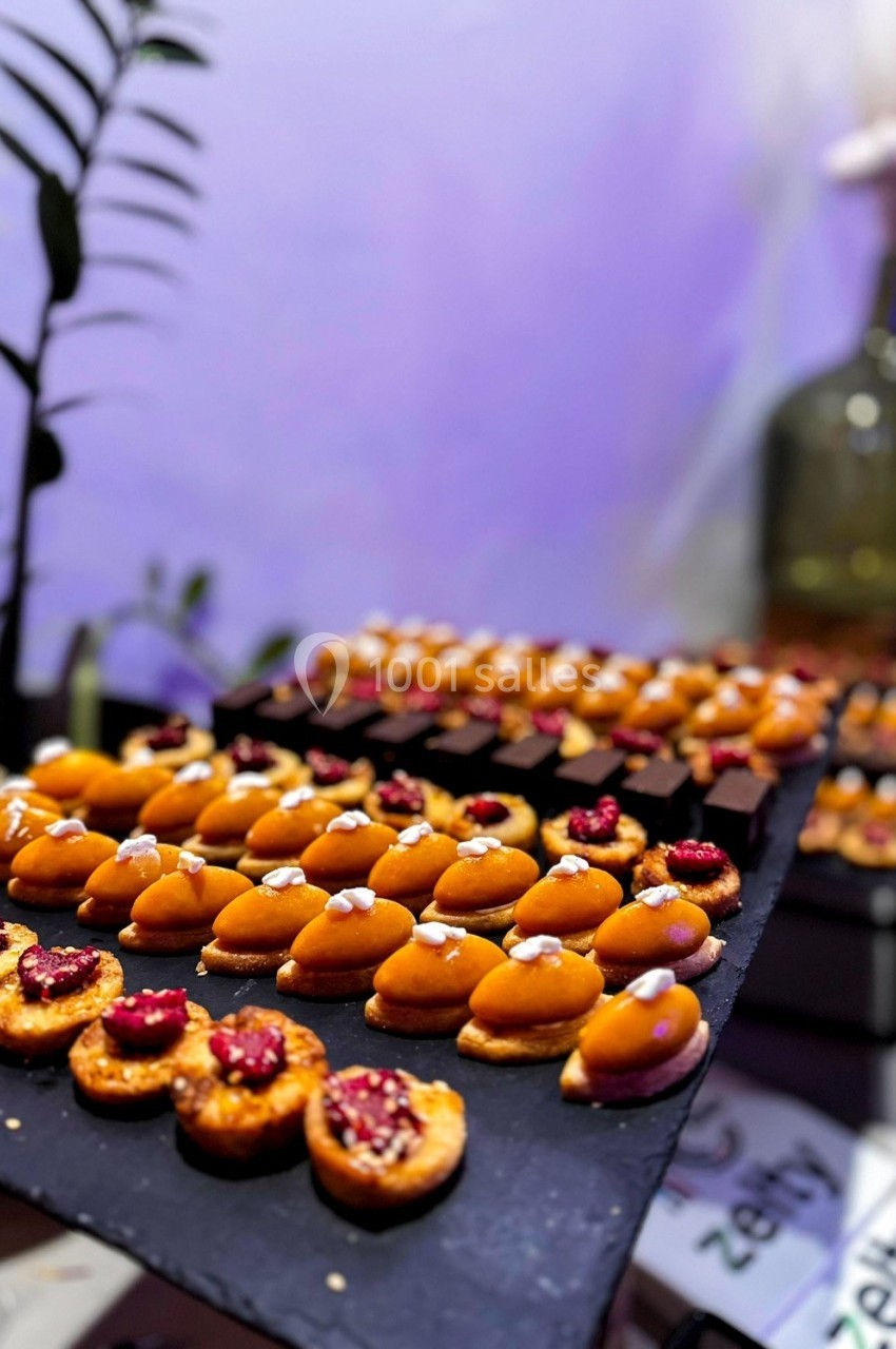 Plateau de mignardises variées, comprenant des tartelettes aux fruits et des bouchées sucrées, présenté sur une ardoise.