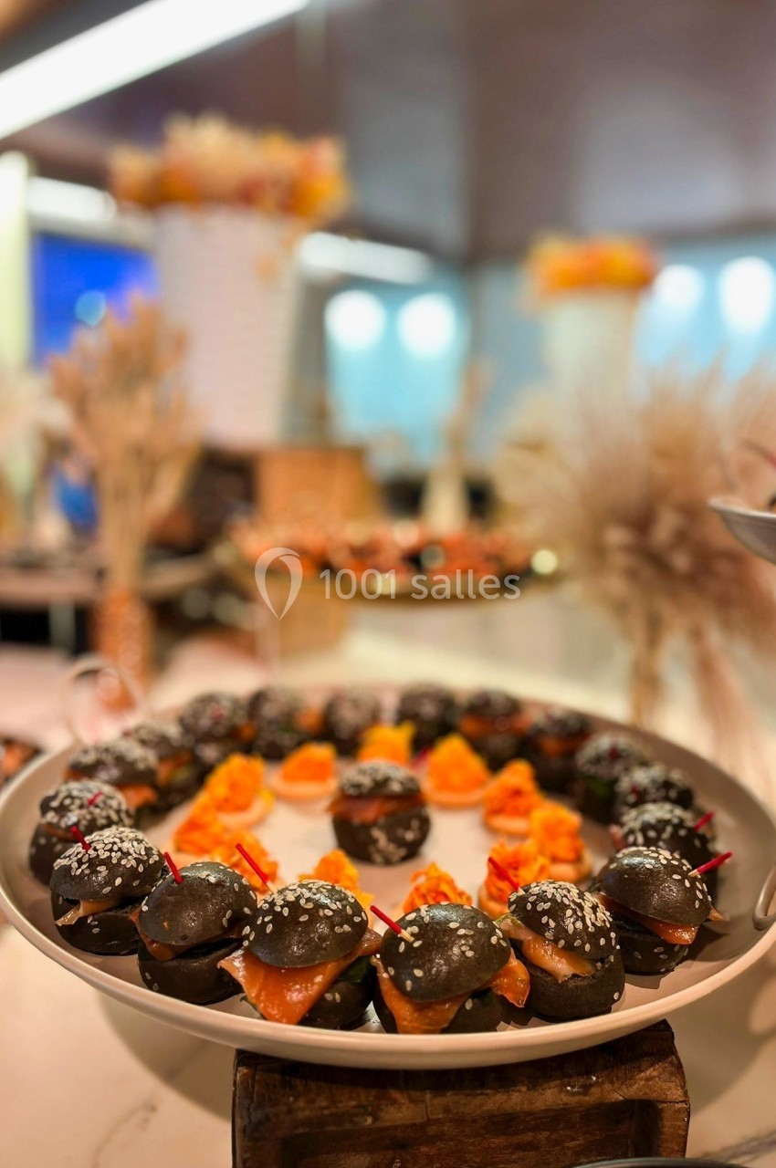Plateau de petits choux noirs garnis, disposés en cercle sur une table décorée de fleurs séchées.