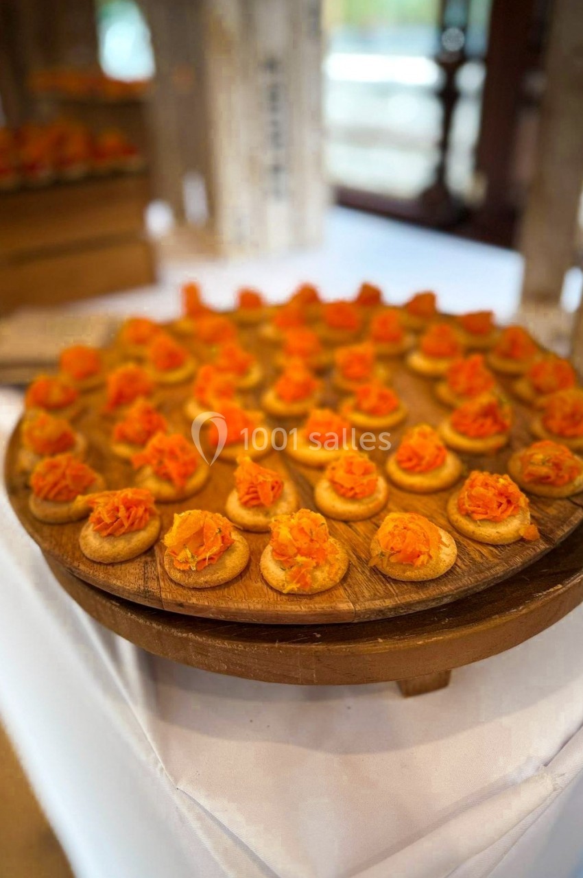 Plateau de bouchées apéritives garnies de saumon fumé, disposé sur une table recouverte d'une nappe blanche.