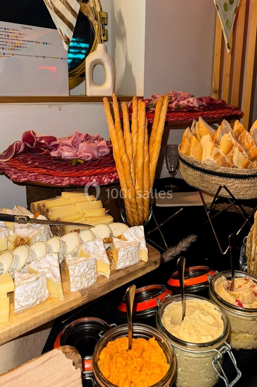 Plateau de charcuteries, fromages, pains et tartinades disposés sur une table pour un buffet ou apéritif.
