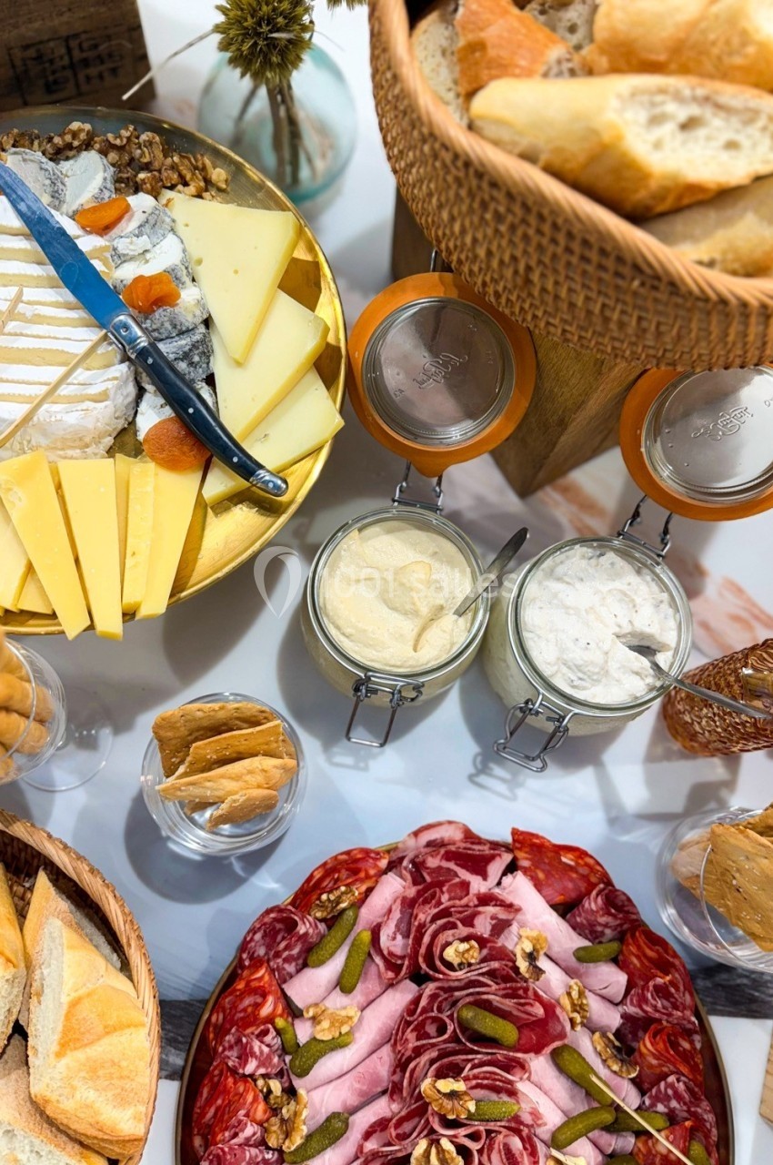 Plateau de charcuterie, fromages, pains et condiments disposés sur une table pour un repas convivial.