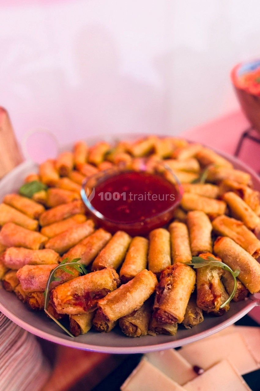 Assiette de petits rouleaux de printemps frits disposés en cercle autour d'un bol de sauce rouge.