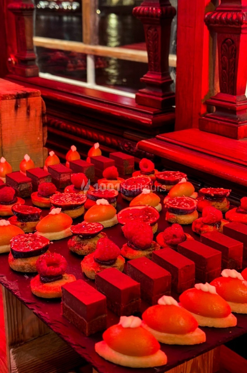 Plateau de desserts variés comprenant des pâtisseries et des chocolats, présenté dans un décor chaleureux en bois rouge.