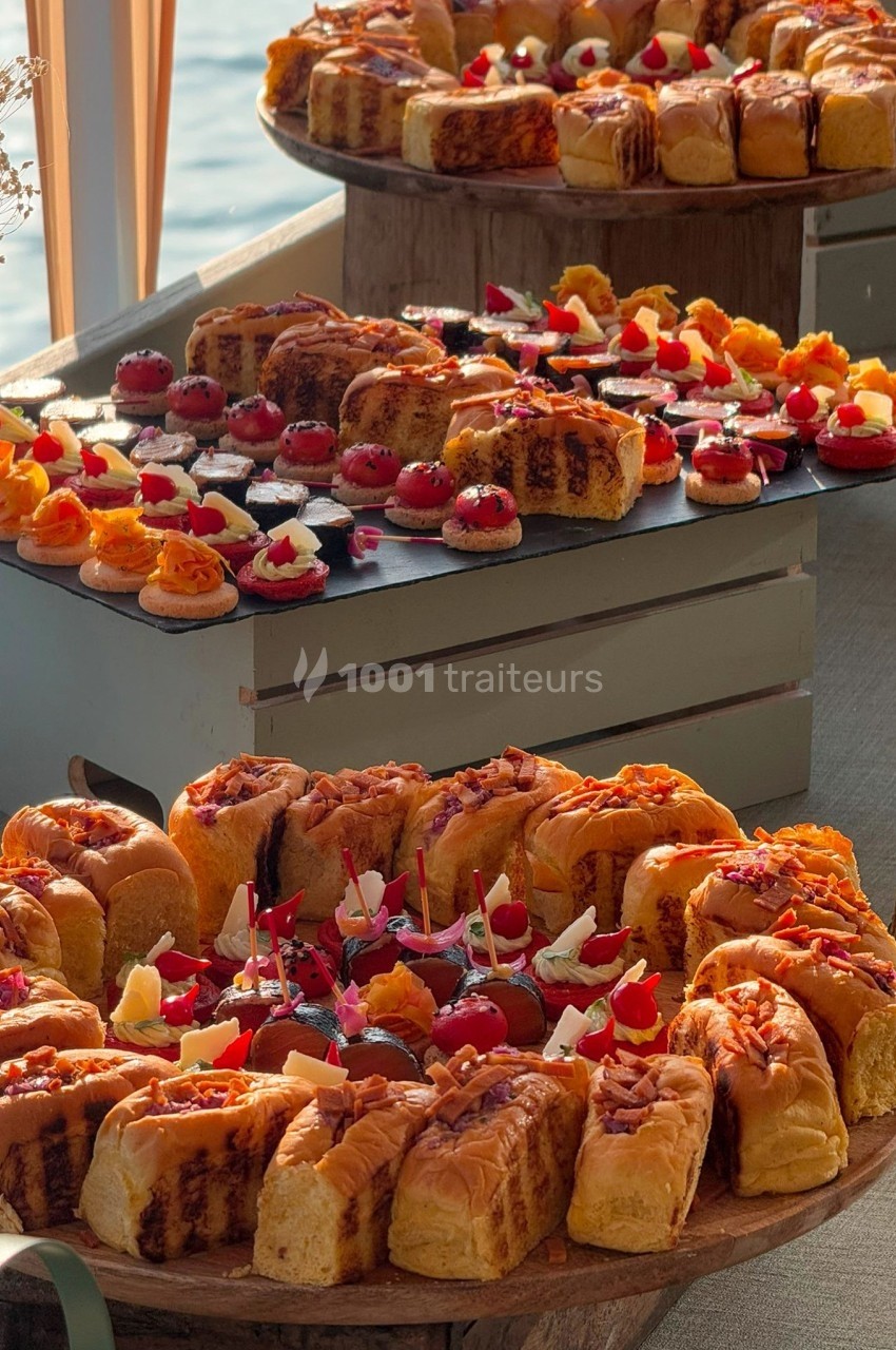 Buffet de pâtisseries et amuse-bouches variés disposés sur des plateaux en bois dans un cadre lumineux.