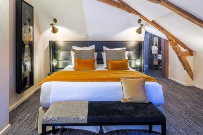 Chambre lumineuse avec lit double, bureau, télévision, grande fenêtre et salle de bain attenante visible.
