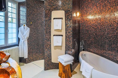 Chambre lumineuse avec lit double, bureau, télévision, grande fenêtre et salle de bain attenante visible.