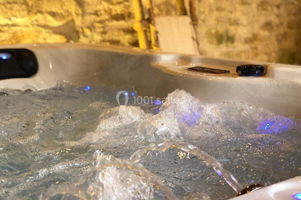 Eau bouillonnante d'un jacuzzi en fonctionnement dans un espace intérieur aux murs en pierre.