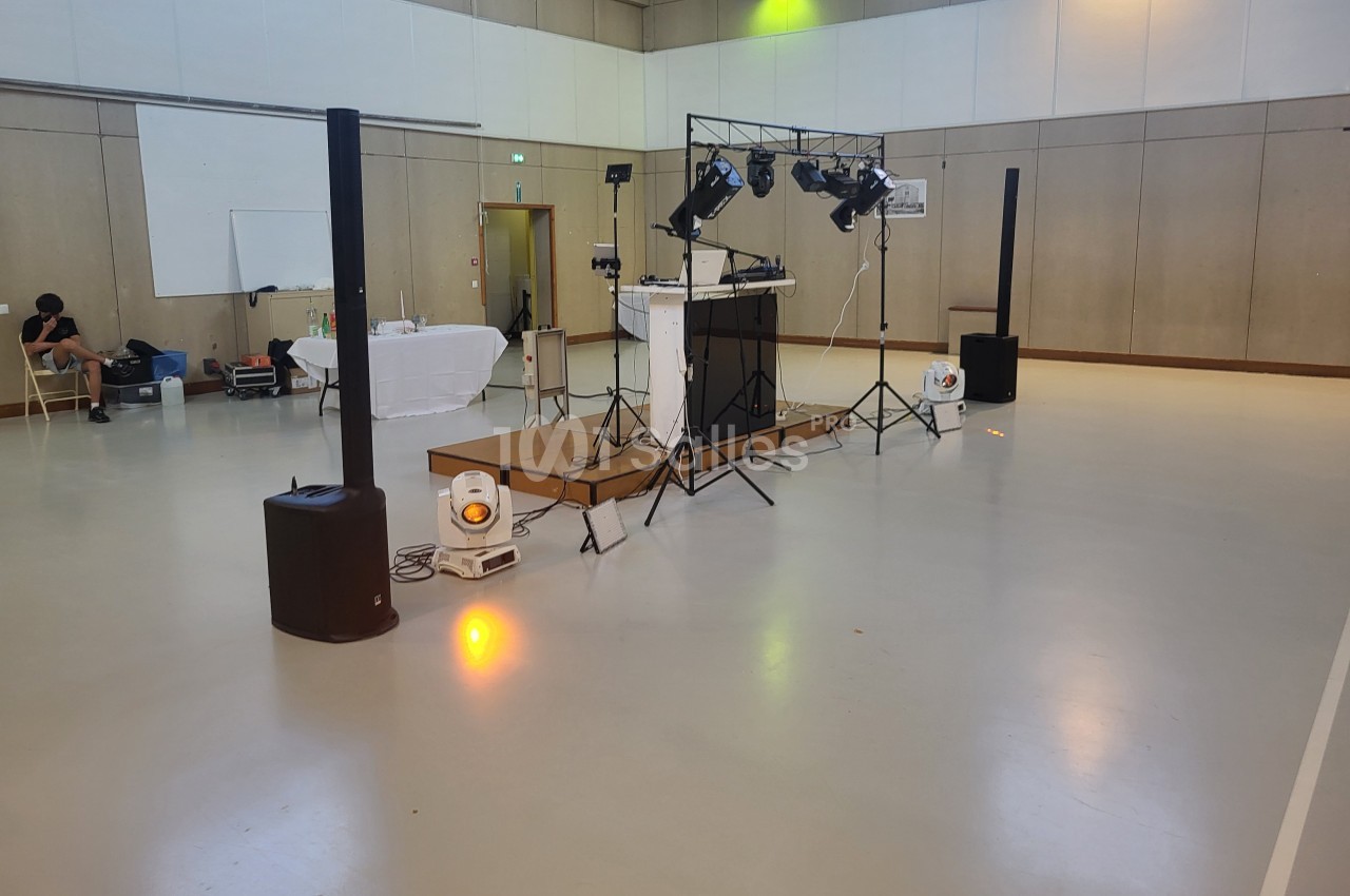 Installation de matériel de sonorisation et d'éclairage dans une salle polyvalente vide.