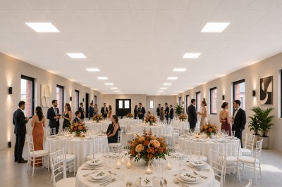 Salle de réception élégante avec tables décorées de fleurs orange et invités debout discutant.