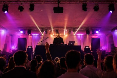 Miniature DJ Montpellier (Hérault) - Essentiel Vocal #4 Un DJ mixant de la musique lors d'une soirée festive avec des invités dans une salle éclairée par des lumières colorées.