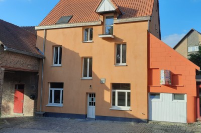 Miniature Location salle Linkebeek (Brabant flamand) - Ferme Holleken Hoeve #12 Façade d'une maison orange à trois étages avec toit en tuiles, entourée de bâtiments en briques et d'une cour pavée.