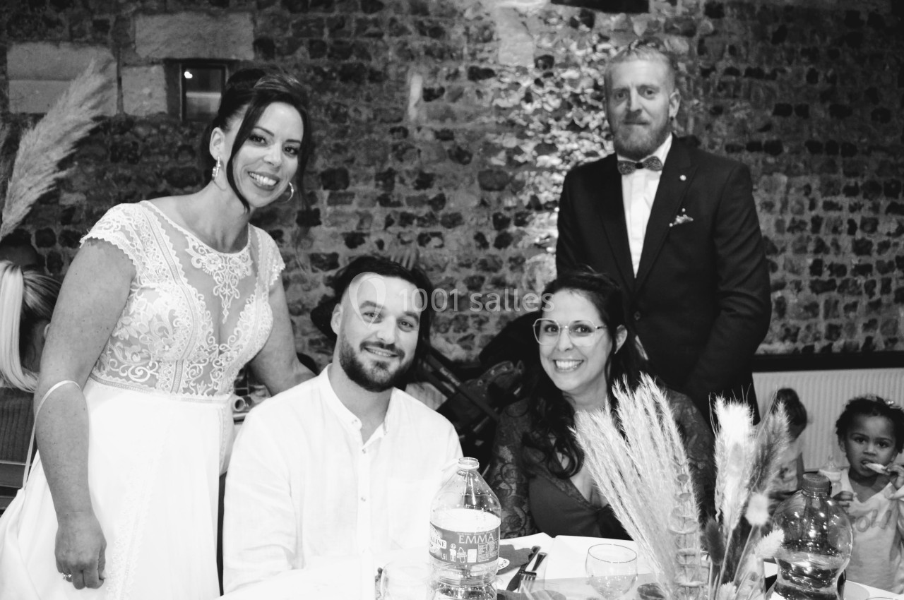 Un groupe de personnes posant autour d'une table lors d'un événement dans une salle en pierre.