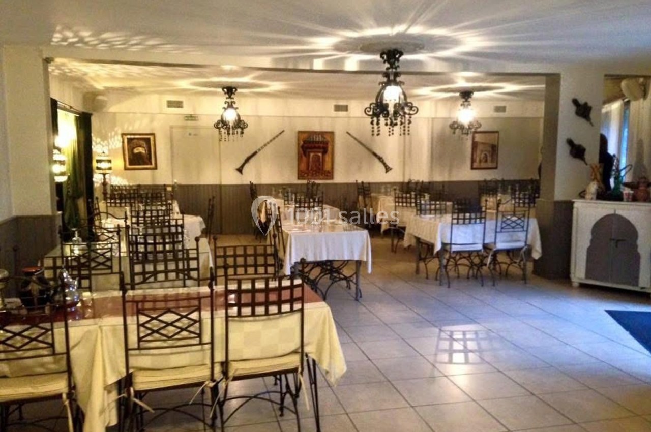 Salle de restaurant lumineuse avec tables dressées, chaises en métal et décorations murales traditionnelles.