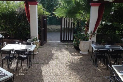 Miniature Location salle La Valette-du-Var (Var) - Les Portes de l'Orient #12 Terrasse extérieure avec tables et chaises en métal, entourée de plantes et ouverte sur un portail en bois.