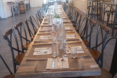 Table dressée avec verre, fourchette et serviette dans un restaurant rustique avec murs en pierre et menu en arrière-plan.