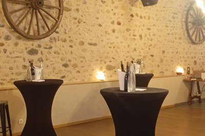 Table dressée avec verre, fourchette et serviette dans un restaurant rustique avec murs en pierre et menu en arrière-plan.