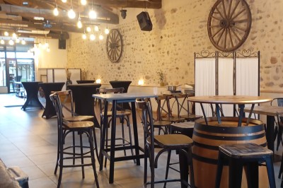 Table dressée avec verre, fourchette et serviette dans un restaurant rustique avec murs en pierre et menu en arrière-plan.