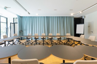 Miniature Location salle Le Havre (Seine-Maritime) - Axès #2 Des personnes discutent dans une salle lumineuse avec des tables garnies de plats variés au premier plan.