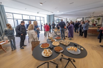 Miniature Location salle Le Havre (Seine-Maritime) - Axès #9 Des personnes discutent dans une salle lumineuse avec des tables garnies de plats variés au premier plan.