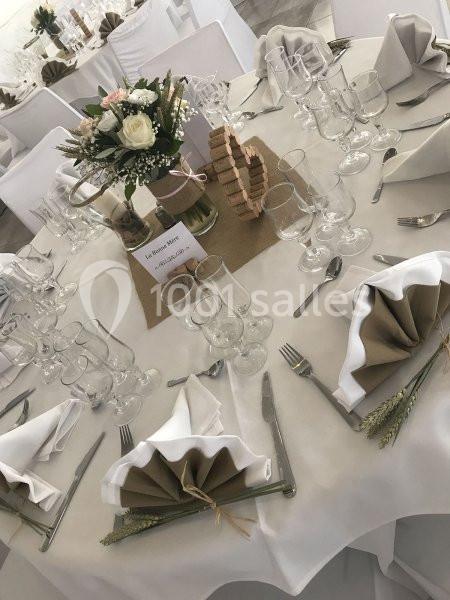 Table de réception décorée avec des serviettes pliées, des fleurs, des couverts et un centre de table rustique.