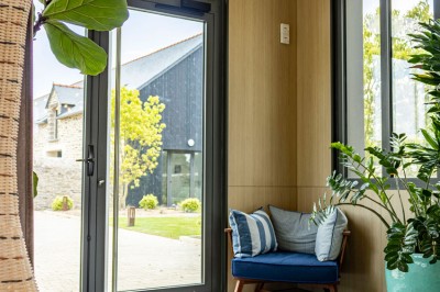 Douche moderne avec paroi vitrée, rideau à motifs noirs, sol en bois et porte blanche adjacente.