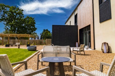 Douche moderne avec paroi vitrée, rideau à motifs noirs, sol en bois et porte blanche adjacente.