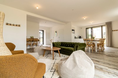 Douche moderne avec paroi vitrée, rideau à motifs noirs, sol en bois et porte blanche adjacente.