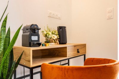 Douche moderne avec paroi vitrée, rideau à motifs noirs, sol en bois et porte blanche adjacente.