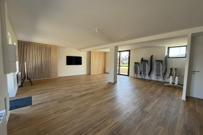 Douche moderne avec paroi vitrée, rideau à motifs noirs, sol en bois et porte blanche adjacente.