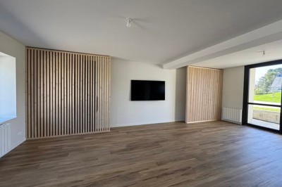 Douche moderne avec paroi vitrée, rideau à motifs noirs, sol en bois et porte blanche adjacente.