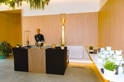 Douche moderne avec paroi vitrée, rideau à motifs noirs, sol en bois et porte blanche adjacente.