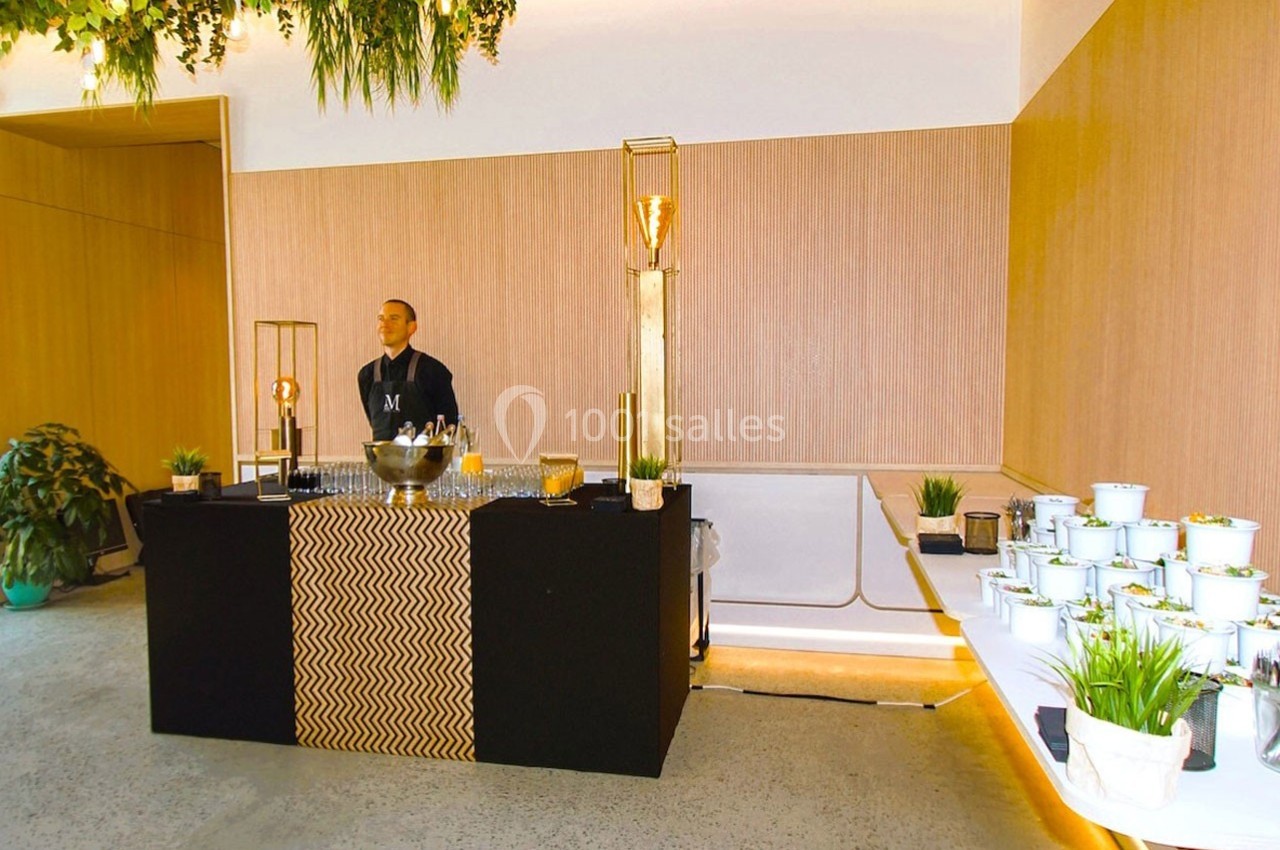 Un buffet élégant avec un serveur derrière un comptoir noir, entouré de plantes et de décorations modernes.