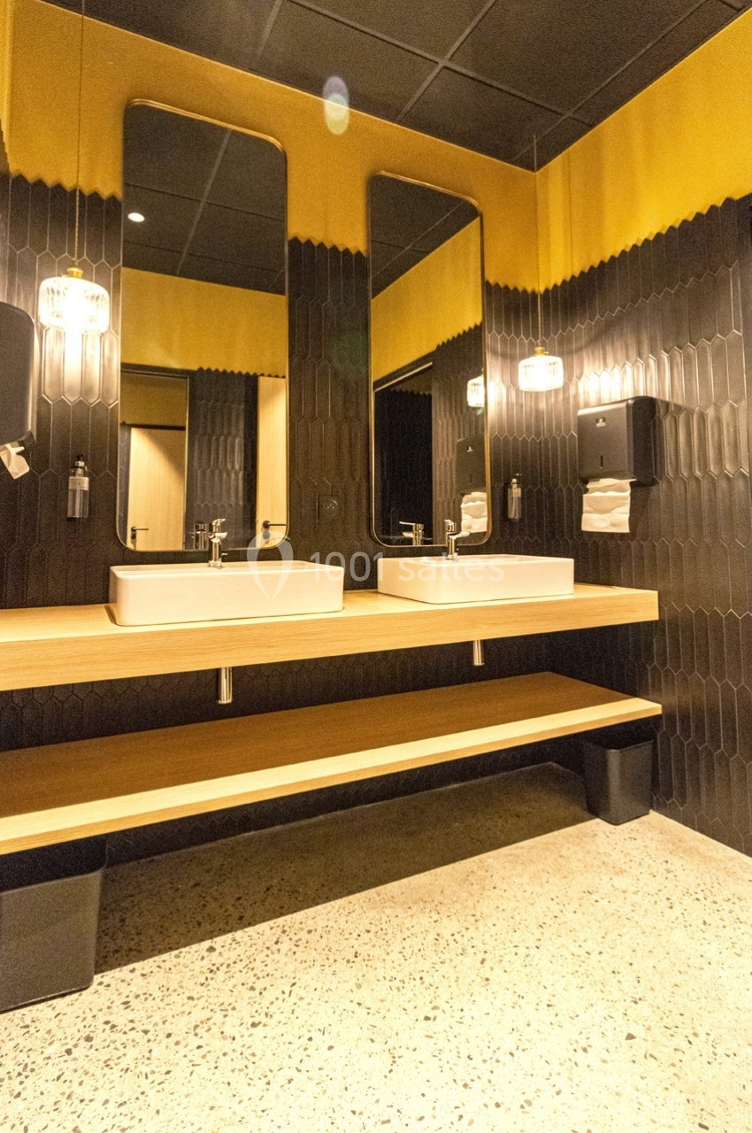 Deux lavabos modernes avec miroirs et éclairage mural dans une salle de bain au design contemporain.