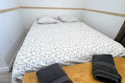Douche moderne avec paroi vitrée, rideau à motifs noirs, sol en bois et porte blanche adjacente.