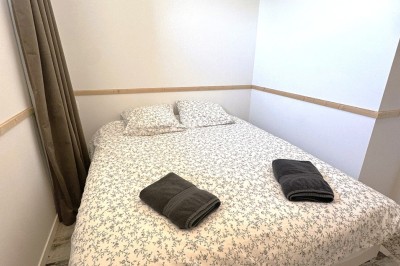Chambre lumineuse avec lit double, parquet, portant à vêtements, chaise et fenêtre de toit.