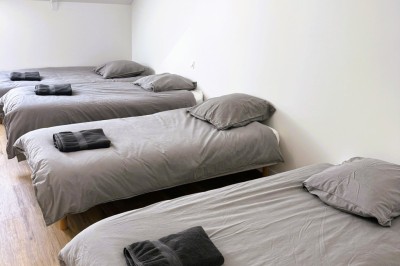 Chambre lumineuse avec lit double, parquet, portant à vêtements, chaise et fenêtre de toit.