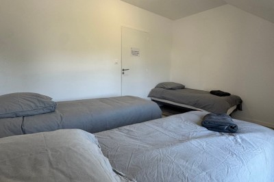 Chambre lumineuse avec lit double, parquet, portant à vêtements, chaise et fenêtre de toit.