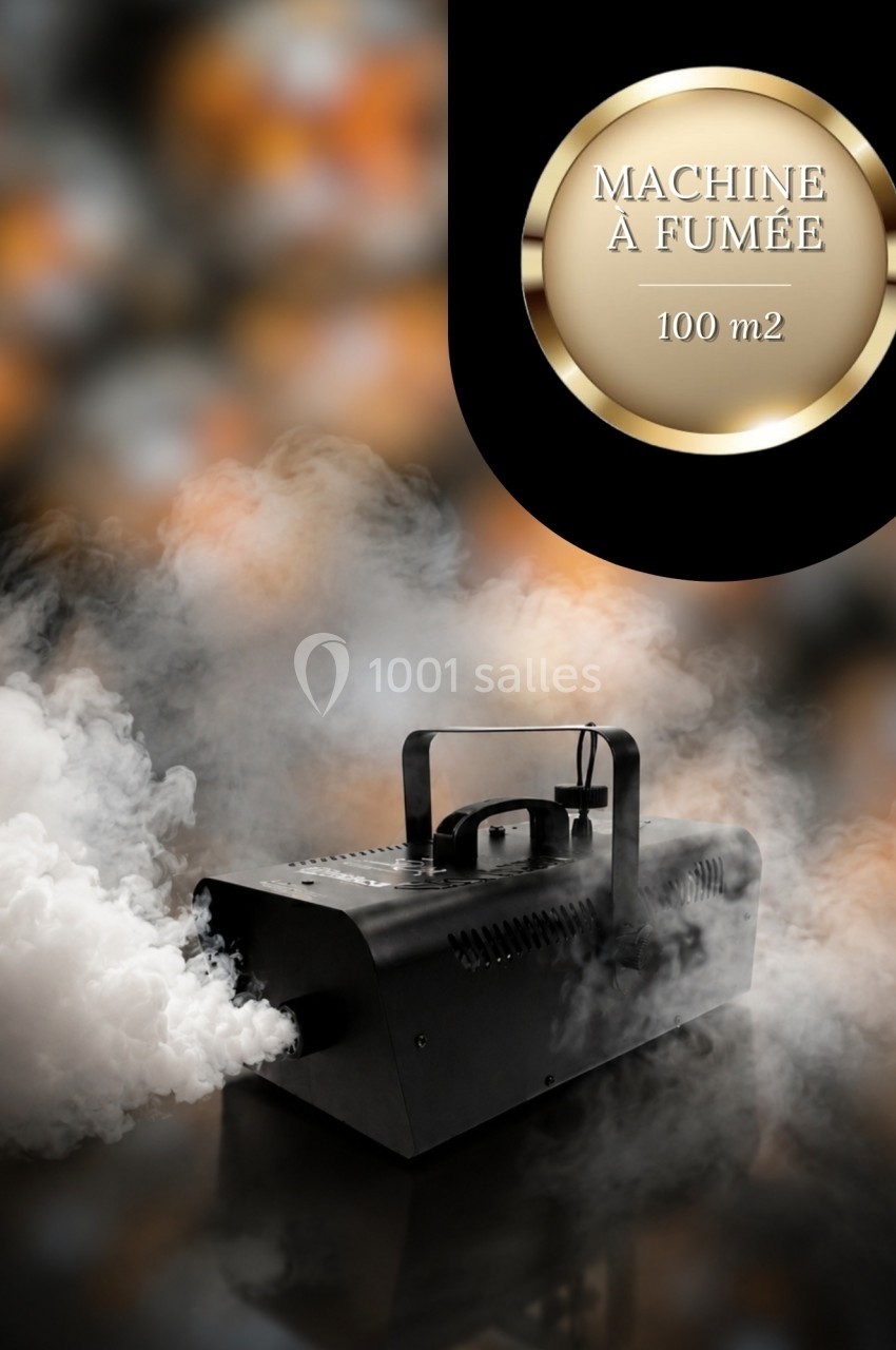 Machine à fumée noire en fonctionnement, dégageant un épais nuage blanc sur un fond sombre.