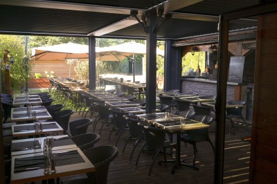 Miniature Location salle Toulouse (Haute-Garonne) - La Cantine d'Horace #2 Brasero allumé avec des flammes vives, placé sur une terrasse extérieure près d'arbustes et de parasols.