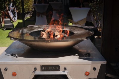 Miniature Location salle Toulouse (Haute-Garonne) - La Cantine d'Horace #11 Brasero allumé avec des flammes vives, placé sur une terrasse extérieure près d'arbustes et de parasols.