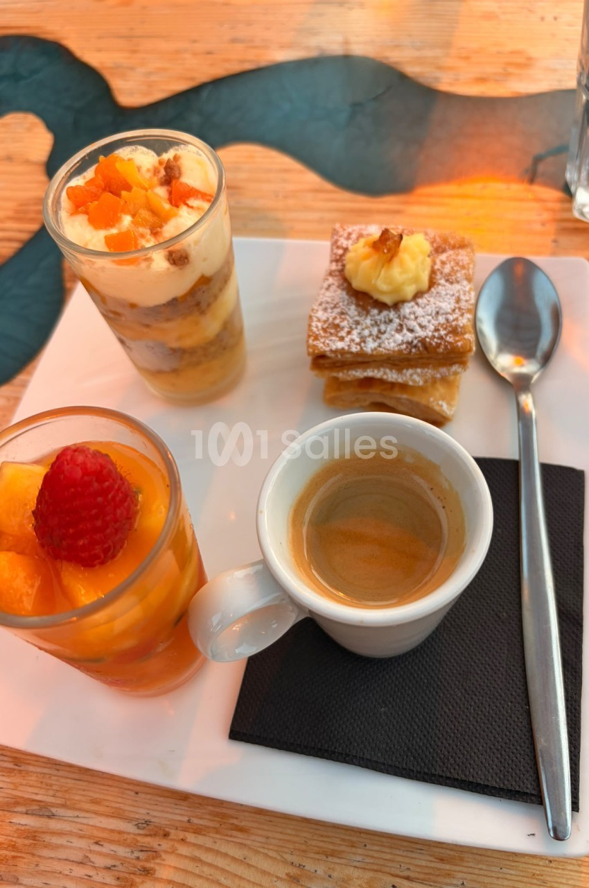Plateau de dégustation avec deux cocktails aux fruits, pâtisserie saupoudrée et espresso sur table en bois.