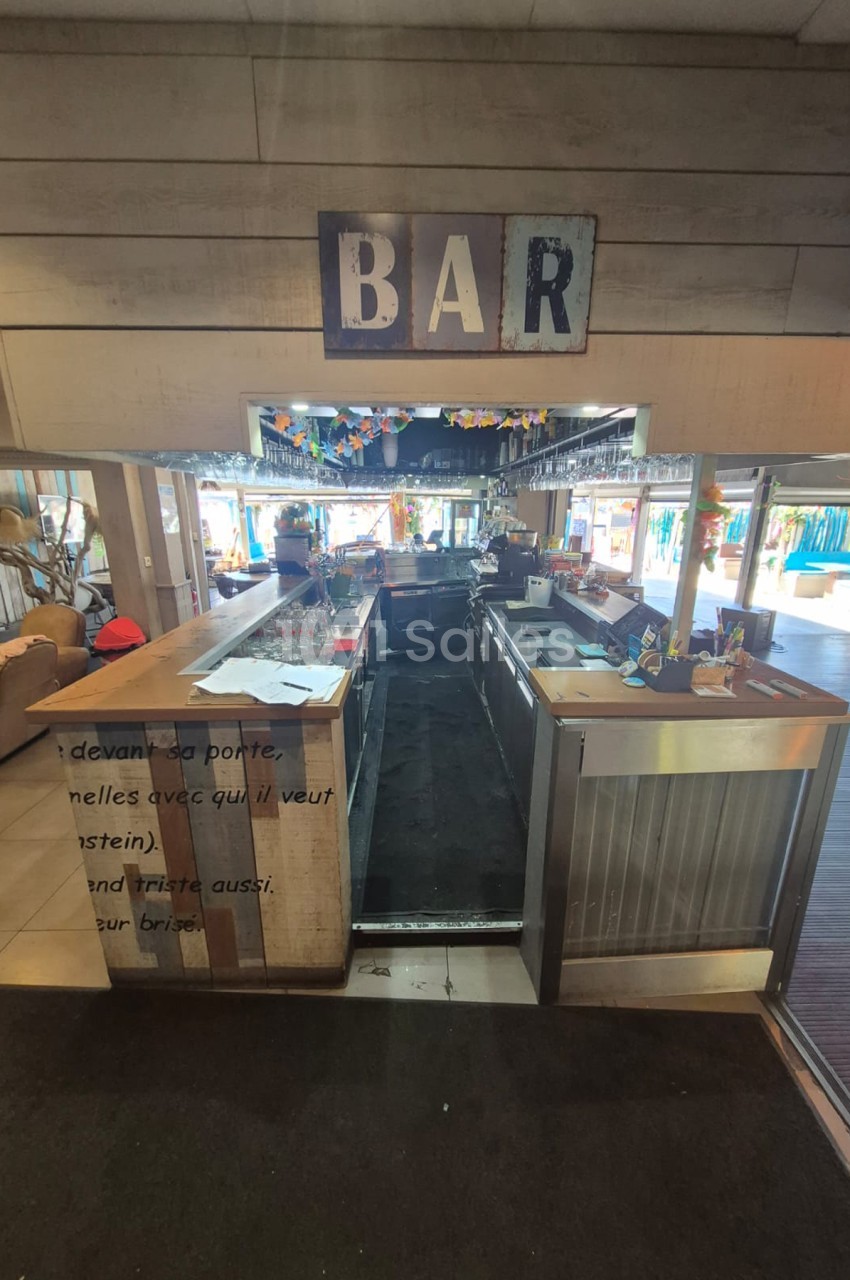 Comptoir de bar en acier inoxydable avec enseigne vintage, vue intérieure d'établissement.