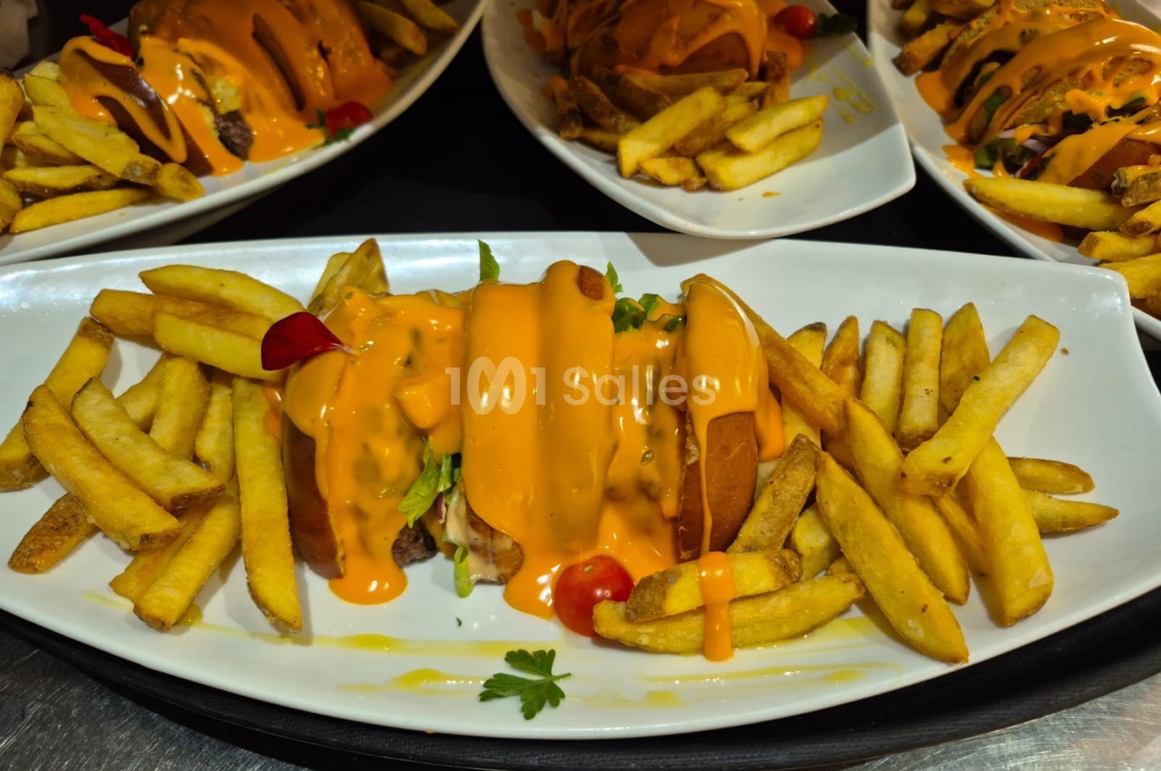 Sandwich garni de poivrons oranges et frites dorées accompagné de sauce sur assiette blanche.